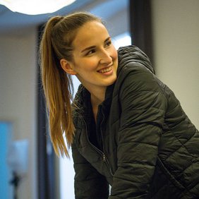 Eine Engagierte der jungen Tafel lacht, während sie etwas aufschreibt.