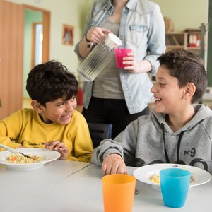 Eine Bundesfreiwilligendienstleistende schenkt Kindern der Tafel Wasser ein.