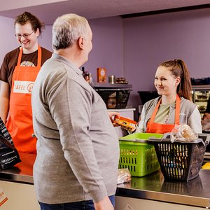 Junge Ehrenamtliche geben Lebensmittel an Tafel-Kundinnen und -Kunden aus.